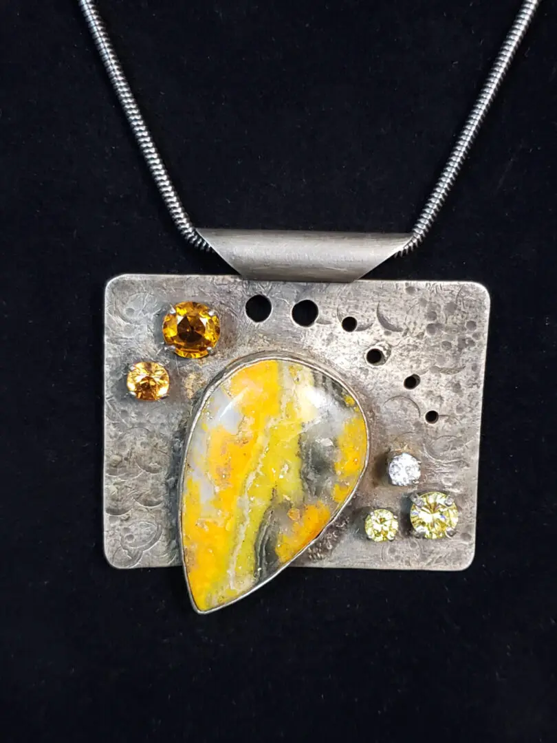 A pendant with a yellow stone and a silver chain.