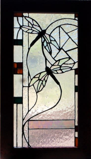 A stained glass window with dragonflies on it.
