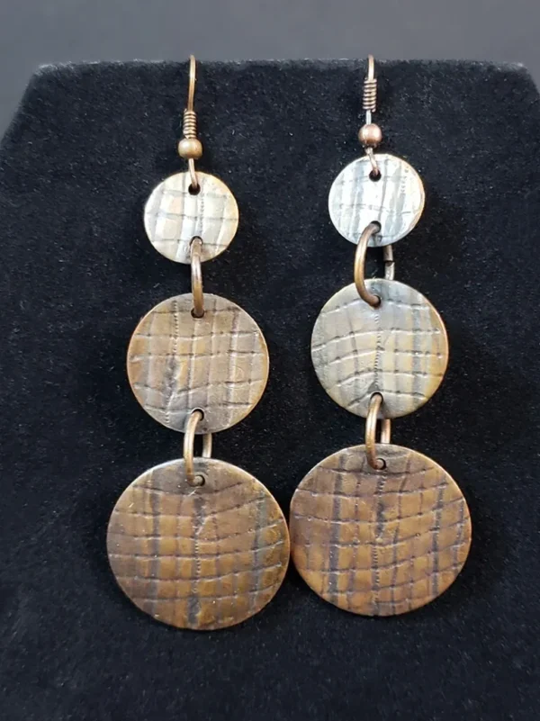 A pair of Copper Stamped Earrings with three circular discs on them.