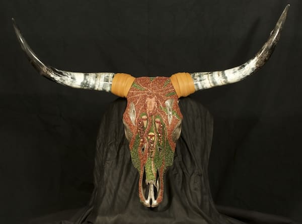 A cow skull with colorful horns on a black background.