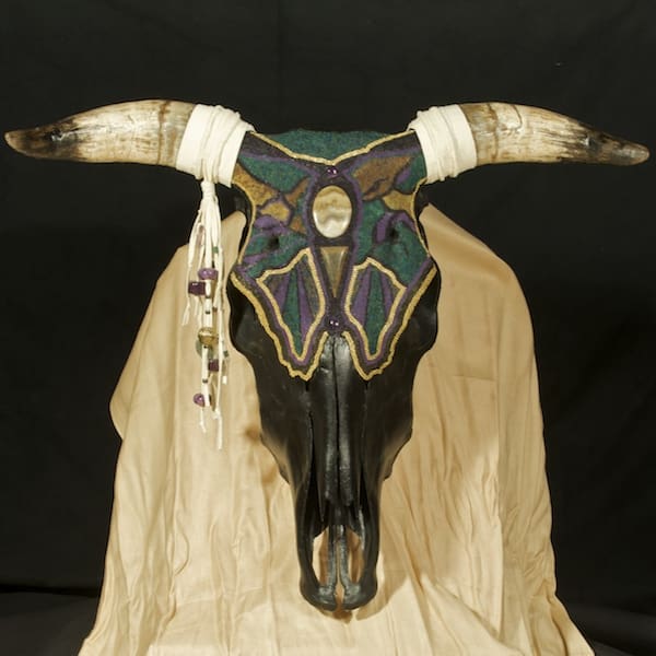 A cow skull with horns and beads on it.