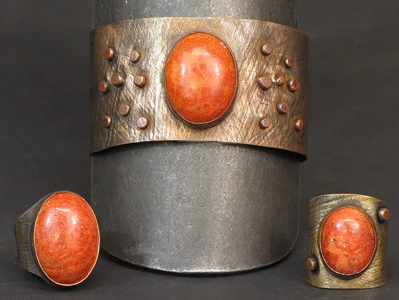 A set of cuffs and a ring with a coral stone.