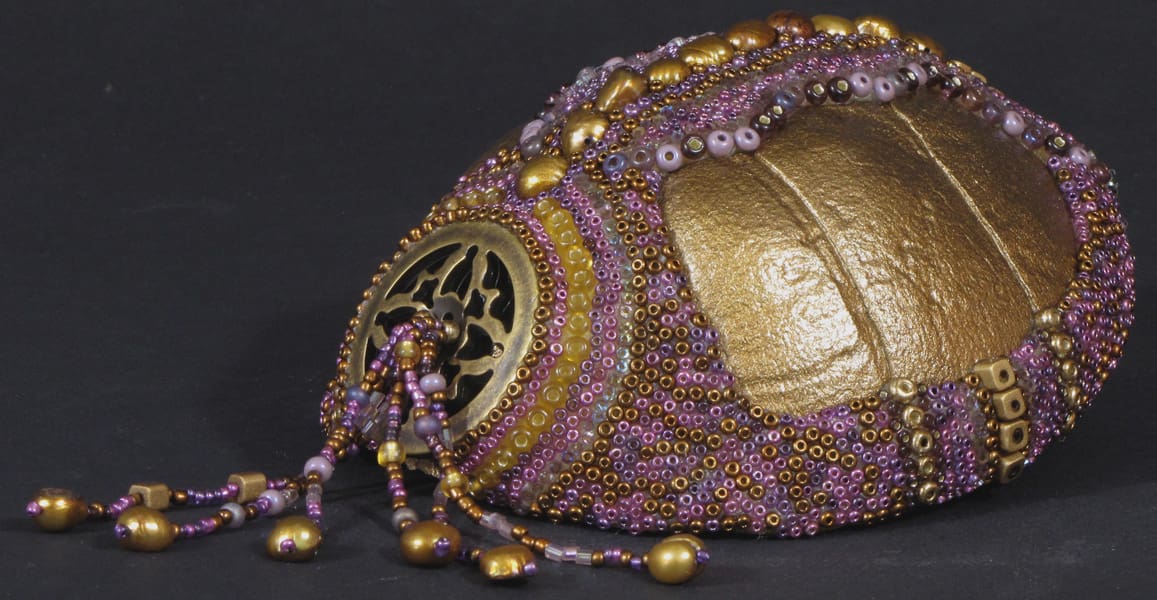 A beaded purse with purple and gold beads.
