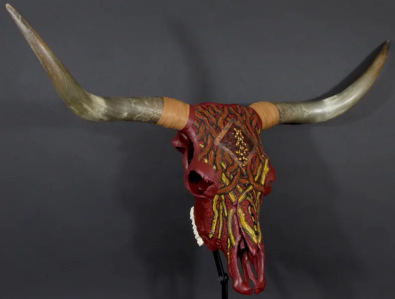 A cow skull with horns and horns on a stand.