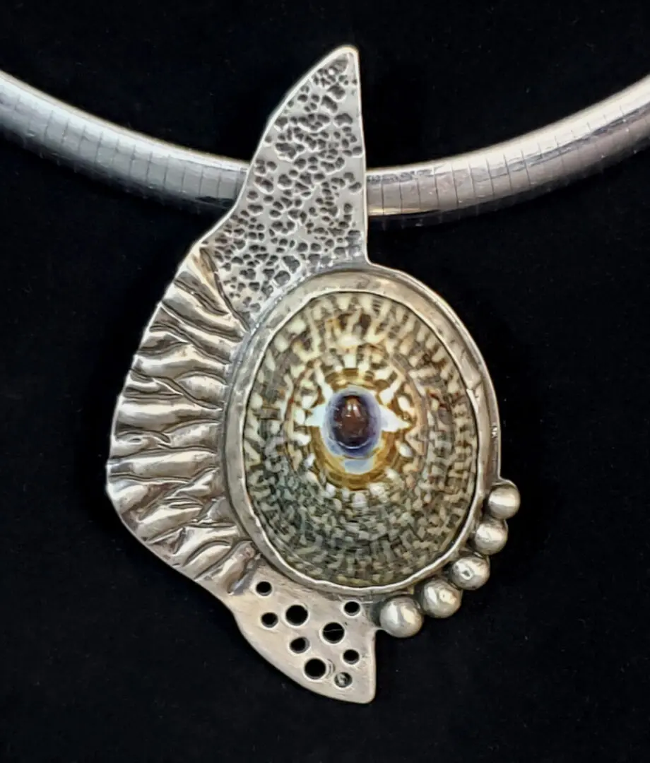 A silver pendant with a shell on it.
