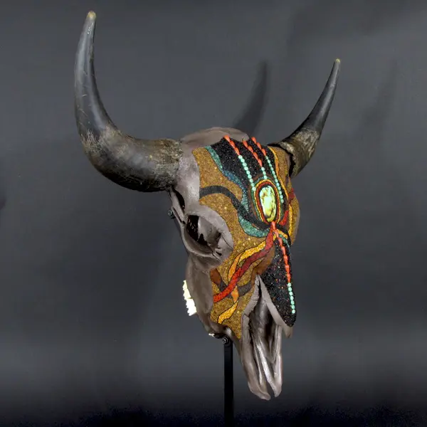 A bull skull with beading and horns on a stand.