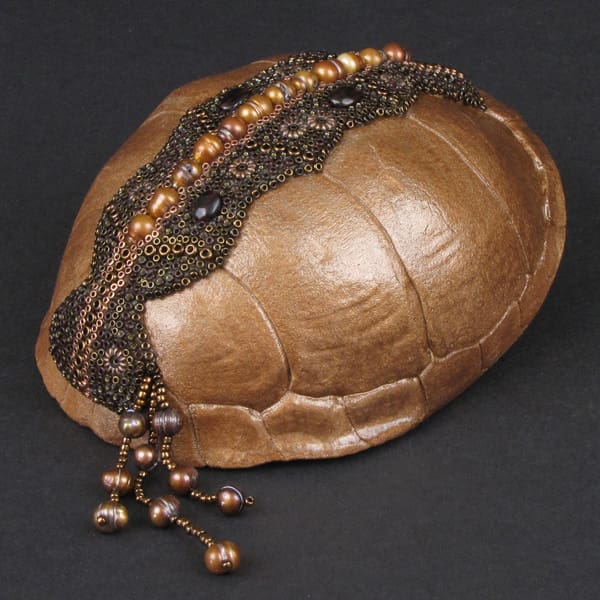 A tortoise shell with beading and pearls.