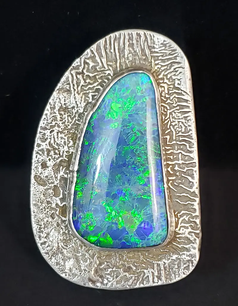 An opal and silver brooch with a blue stone.