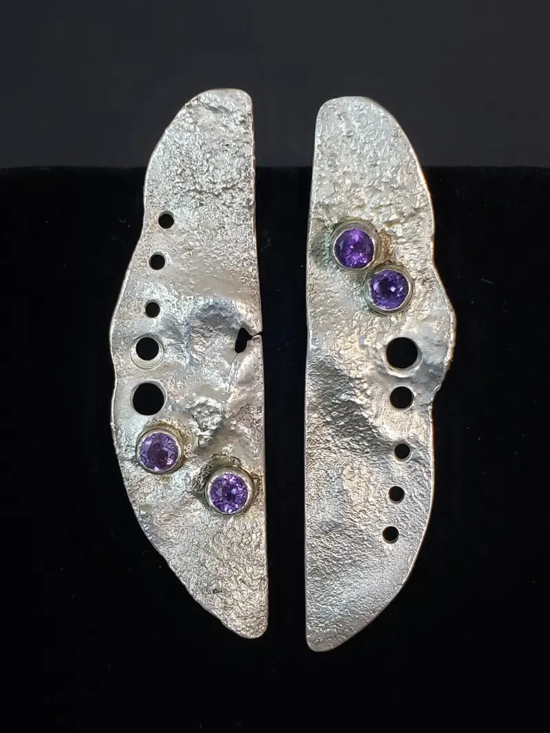 A pair of silver earrings with purple stones.