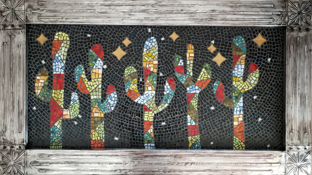 A mosaic of cactus trees in a wooden frame.