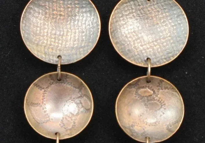 A pair of Copper Stamped Dome Earrings with three metal circles on them.