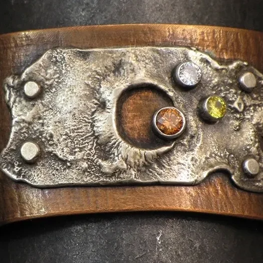A copper cuff with stones on it.