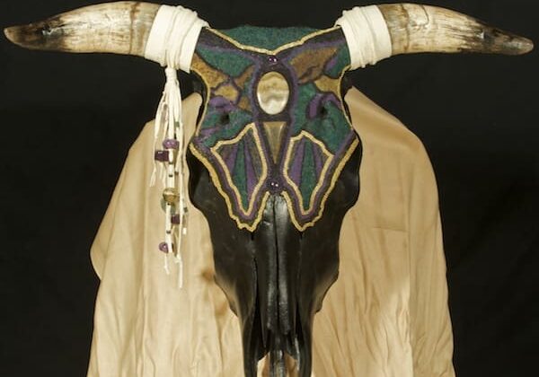A cow skull with horns and beads on it.