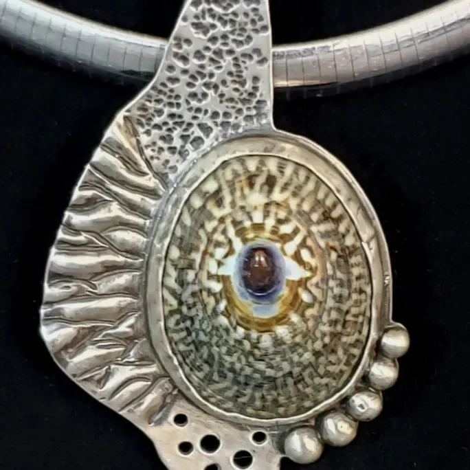 A silver pendant with a shell on it.